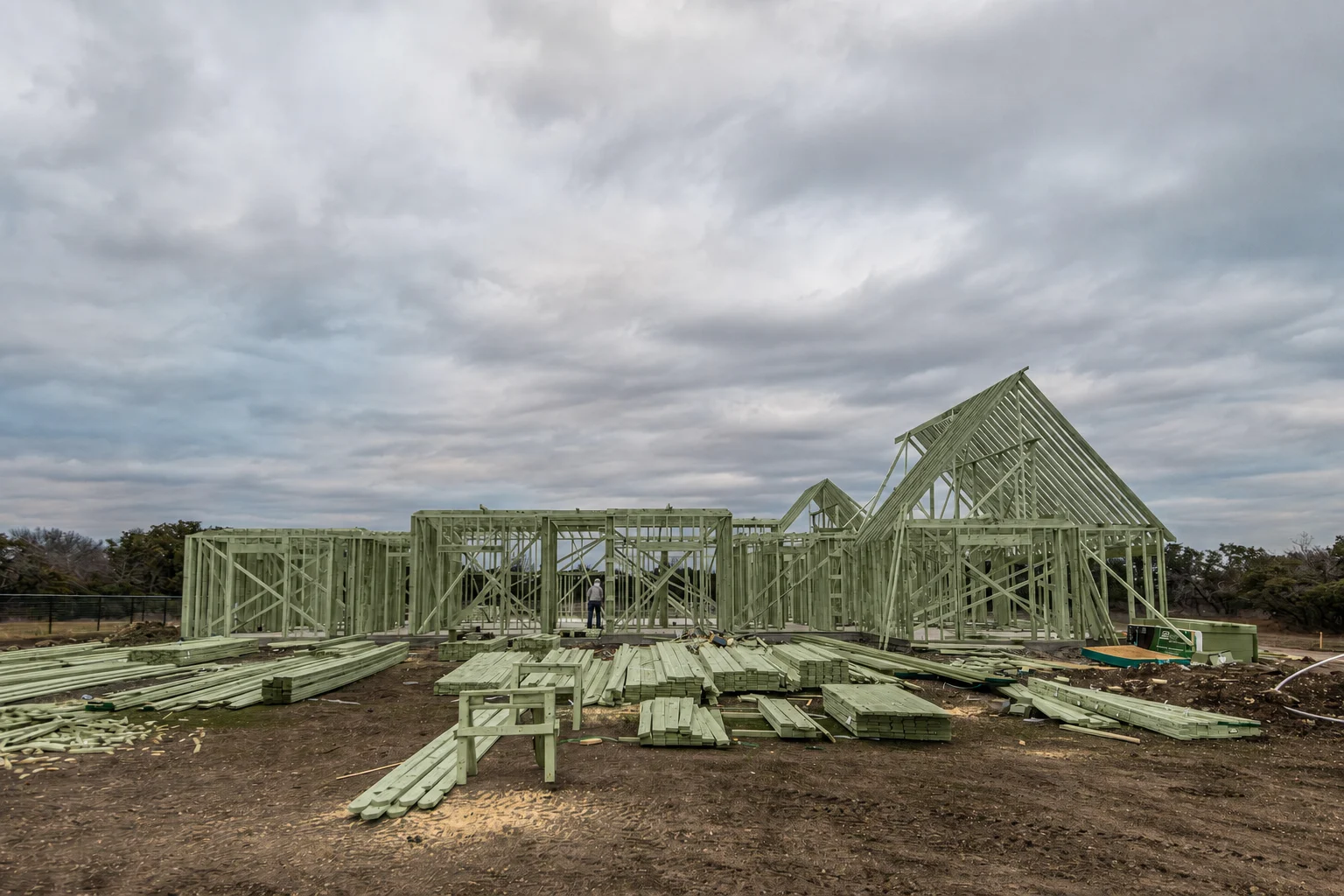 Residential construction photograph with a green treatment-color visualization applied to the framing